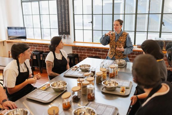A tour guide demonstrates a part of the Chocolatier Tour at Wellington Chocolate Factory to a group of people listening.