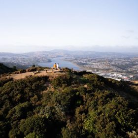 Two people sit on the bench at the Rangituhi Lookout.