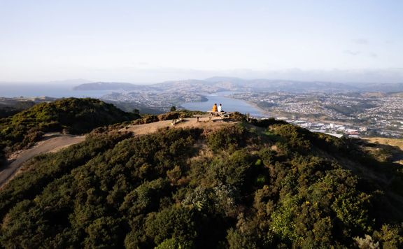 Two people sit on the bench at the Rangituhi Lookout.