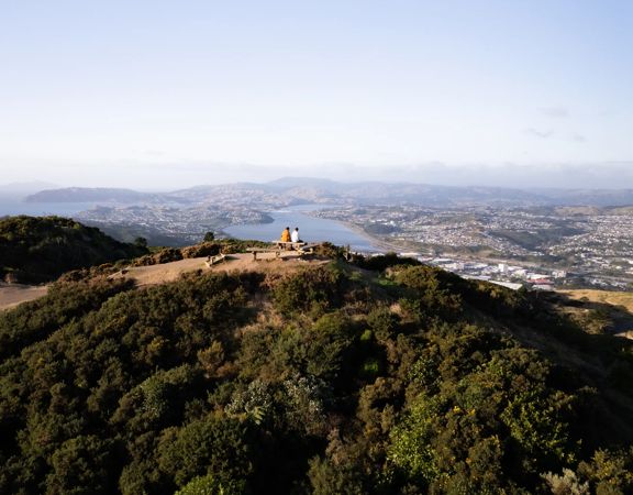 Two people sit on the bench at the Rangituhi Lookout.