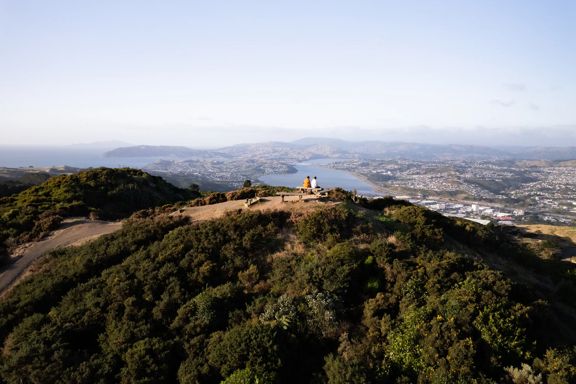 Two people sit on the bench at the Rangituhi Lookout.