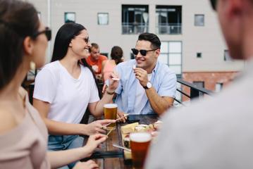 Four friends enjoy beers and a charcuterie board on the patio at Fortune Favours, a brewery in Te Aro, Wellington.