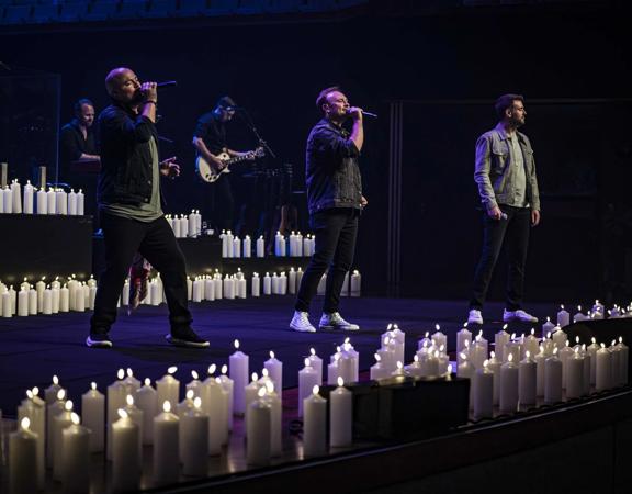 Three singers and two supporting musicians perform a candlelit concert.