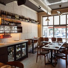 Inside Rosella restaurant and bar. The large window on the ground floor lets in plenty of light with seats lining a narrow bench along the window.