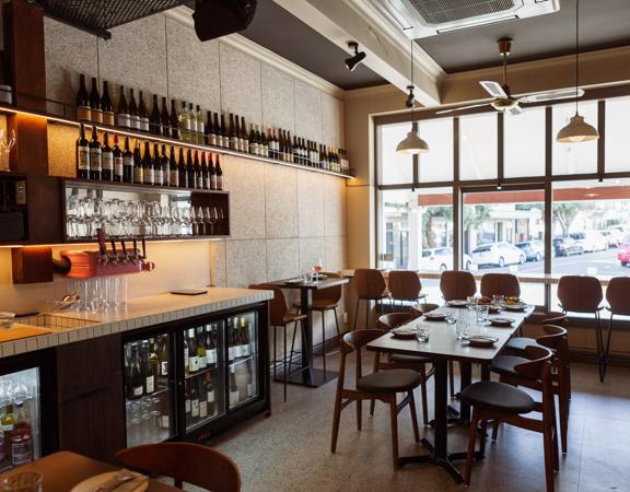 Inside Rosella restaurant and bar. The large window on the ground floor lets in plenty of light with seats lining a narrow bench along the window.