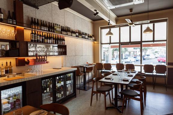 Inside Rosella restaurant and bar. The large window on the ground floor lets in plenty of light with seats lining a narrow bench along the window.