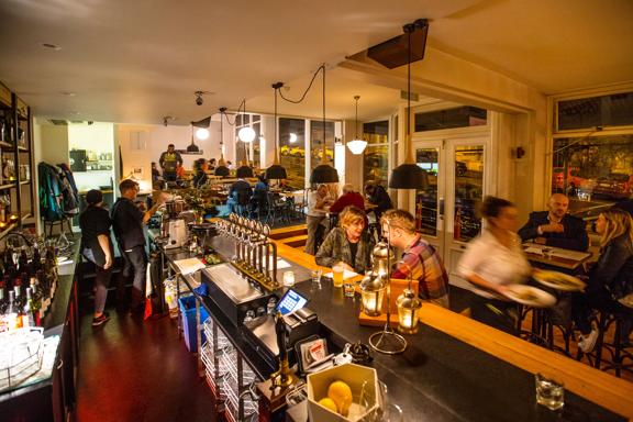 Inside a busy low-lit pub of people enjoying food and drinks.