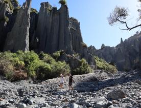 Two people walking along a rocky canyon at the Putangirua Pinnacles track in the Wairarapa. 