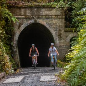 2 people coming out of a tunnel on their bikes on the Remutaka Cycle trail.