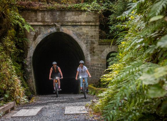 2 people coming out of a tunnel on their bikes on the Remutaka Cycle trail.