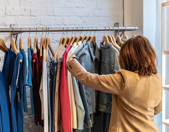 A person sorting through clothing on racks at Caughley.