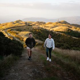 Two people walk up a hill on Farm Road to Rangituhi Summit.