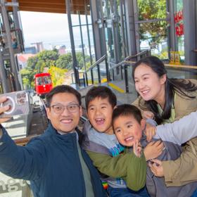 A family of four takes a selfie at the Wellington Cable Car at the Kelburn Terminal.