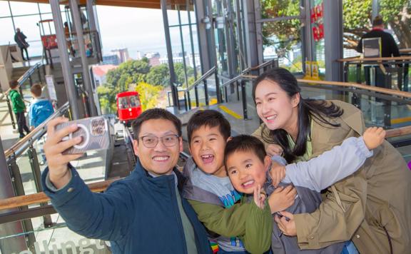 A family of four takes a selfie at the Wellington Cable Car at the Kelburn Terminal.