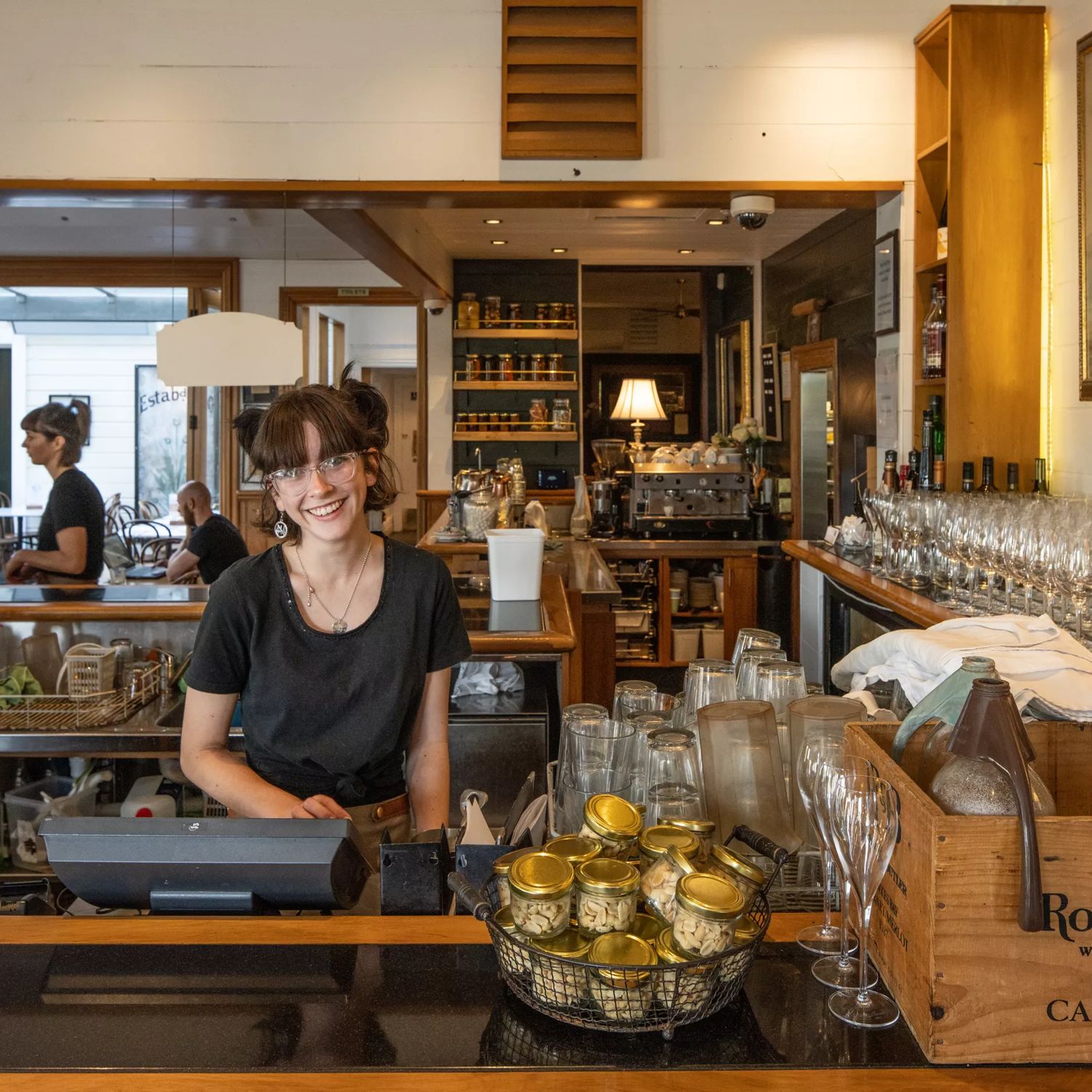 A waiter inside Thistle inn smiling at the camera.