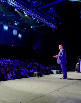 A speaker addressing an audience at Harcourts Conference at the TSB Arena in Wellington.