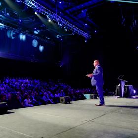 A speaker addressing an audience at Harcourts Conference at the TSB Arena in Wellington.