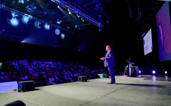 A speaker addressing an audience at Harcourts Conference at the TSB Arena in Wellington.