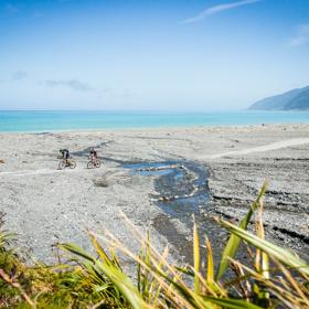 Two cyclists on the beach in Palliser Bay, at the entrance to the Wild Coast Section of the Remutaka Cycle Trail.