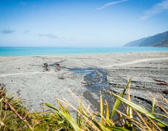 Two cyclists on the beach in Palliser Bay, at the entrance to the Wild Coast Section of the Remutaka Cycle Trail.