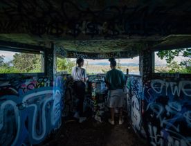Two people explore a graffitied bunker.