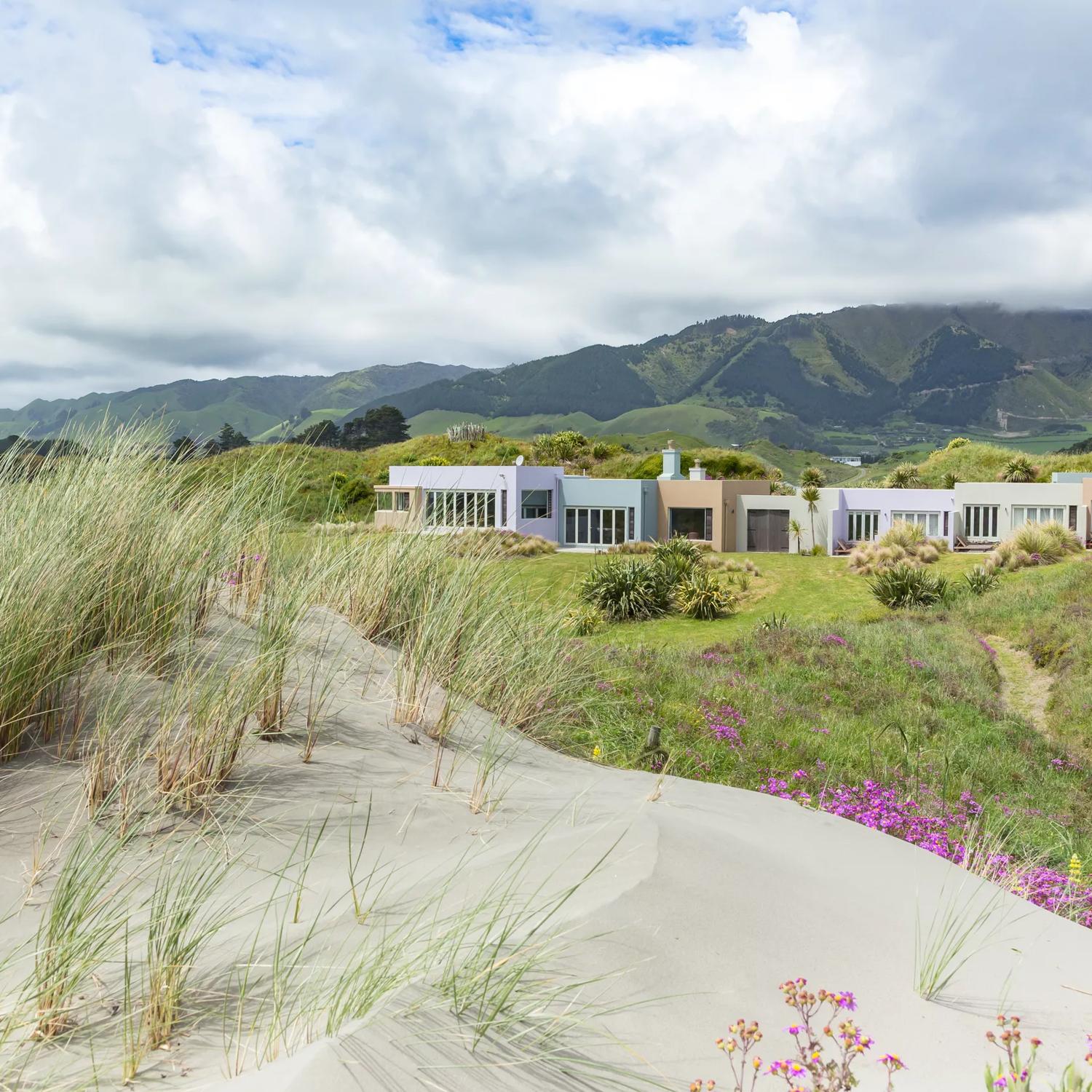 On the sand dunes looking over to Atahuri Lodge on the Kāpiti Coast, with mountains in the background.