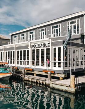 The exterior of Dockside, floating on the water off Queens Wharf, with a boat parked up beside.