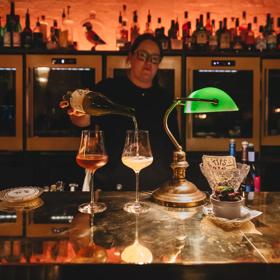 A bartender stands behind the bar pouring two glasses of wine at Puffin, a chic winebar in Te Aro, Wellington.