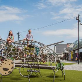 Two children climbing on a half-sphere climbing structure on a playground in Cobham Court, Porirua. 