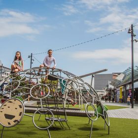 Two children climbing on a half-sphere climbing structure on a playground in Cobham Court, Porirua.