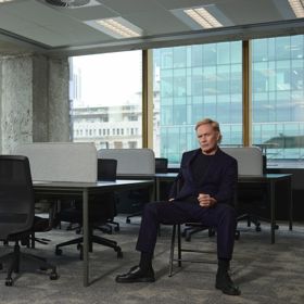Shayne P Carter sits in an empty, modern, open-concept office.
