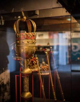 A display case in the Wellington Museum with four jeweled crowns and three gold septors.