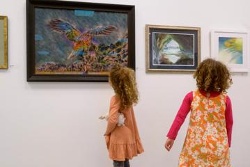 Two children look at paintings in a gallery.