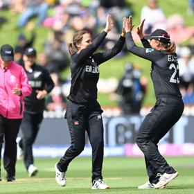 2 Cricket players high fiving on the field.