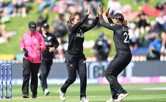 2 Cricket players high fiving on the field.