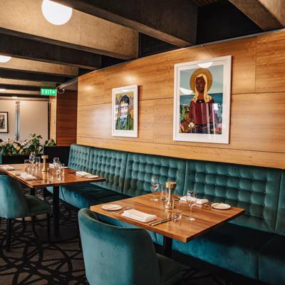 The interior of Bellamys, a restaurant in the Beehive building in Pipitea, Wellington, has green velvet seating and various paintings on the wall by Rita Angus.