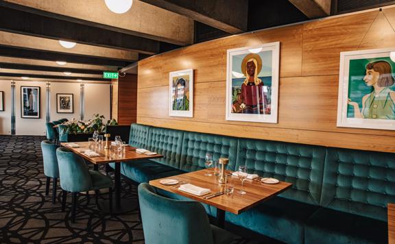 The interior of Bellamys, a restaurant in the Beehive building in Pipitea, Wellington, has green velvet seating and various paintings on the wall by Rita Angus.