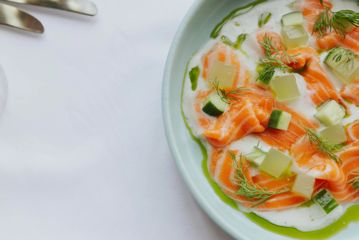 Fresh salmon and cucumber artfully diplayed on a plate with cubes of jelly, fennel and olive oil.