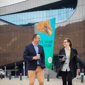 Two business conference attendees walk outside of Tākina Wellington Convention & Exhibition Centre.