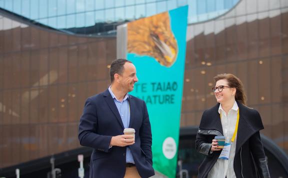 Two business conference attendees walk outside of Tākina Wellington Convention & Exhibition Centre.