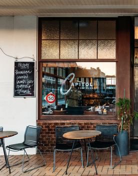 The exterior of Capitol Restaurant on Kent Terrace. A handwritten blackboard shows the daily specials, and stained glass windows create a moody look.