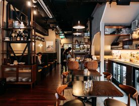 The interior of Rosella Wine Bar. The space has dark wood, modern furniture and soft lighting.