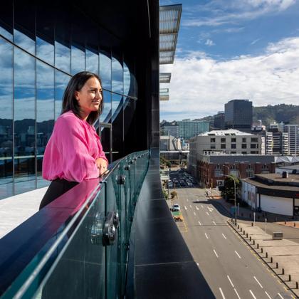 A person in a pink blouse stands on the balcony at Tākina Wellington Convention & Exhibition Centre.