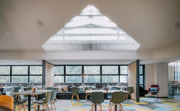 Dining room inside Atura Hotel with many chairs and tables.