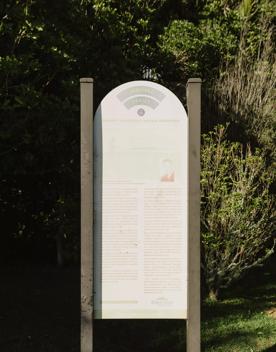 A sign at Barry Hadfield Nikau Reserve with faded text and images.