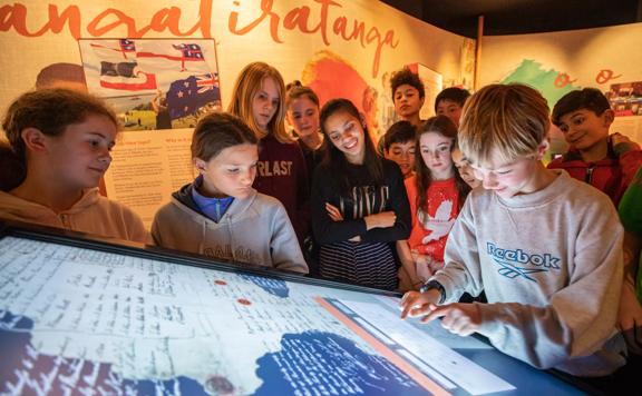 Students crowding around an exhibition at The National Library of New Zealand, Te Puna Mātauranga o Aotearoa.