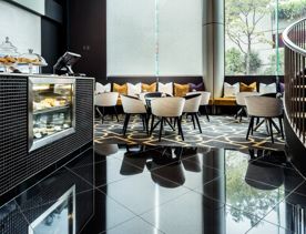 The interior of the Lobby Cafe at the Bolton Hotel in Wellington with a pastry counter, three tables, eight chairs and bench seating.