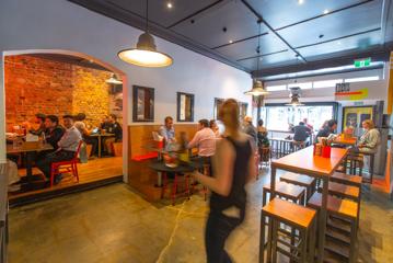 Inside an American-style burger bar. There are people dining while a waitress carries a tray of drinks.