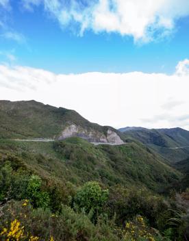 The screen location of Remutaka Summit, wit views of surrounding peaks, lush green bush and steep roads cut into the sides of the mountains.
