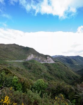 The screen location of Remutaka Summit, wit views of surrounding peaks, lush green bush and steep roads cut into the sides of the mountains.